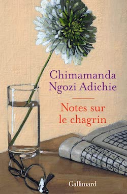  Couverture du livre de chimamanda Ngori Adiche, Notes sur le chagrin, (une fleur dans un verre, une parire de lunette et un journal sur un coin de table)