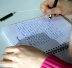 Image d'une page d'écriture et d'une main tenant un stylo