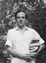 Photo en noir et blanc de François Truffaut, de face, portant des livres sous le bras